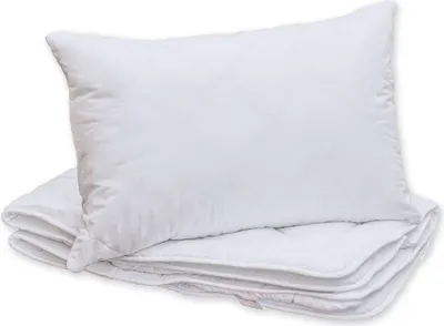 A white pillow is placed on top of a folded white blanket.