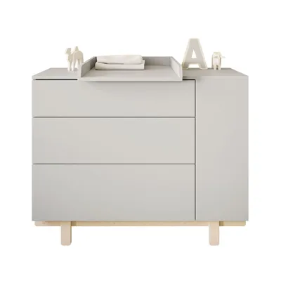 A light gray dresser with a changing station on top, decorated with small figurines and a letter 'A'.