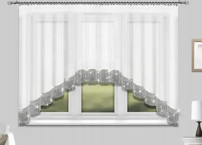 A white sheer curtain with a decorative silver trim is hung on a window.