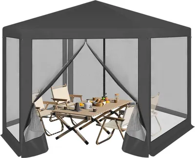 A hexagonal gazebo with mesh walls, set up with a table and chairs inside.
