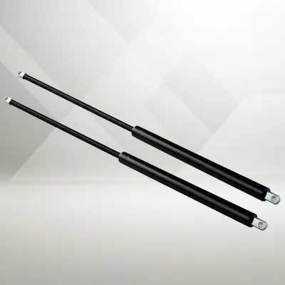 Two black gas springs are shown diagonally on a light gray and white geometric background.