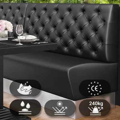 A black leather Chesterfield-style gastro bank seat with decorative buttons, placed next to a table set for dining. Several icons indicating product features are visible at the bottom.