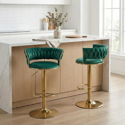 Two emerald green velvet bar stools with gold bases are shown in a modern kitchen setting.