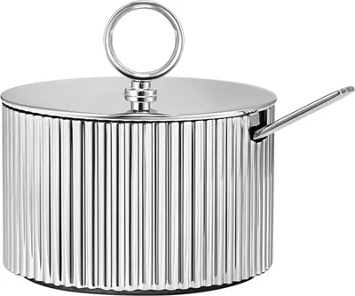 A silver sugar bowl with a lid and spoon, set against a white background.