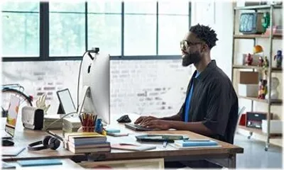 A man is working on a computer in an office setting.