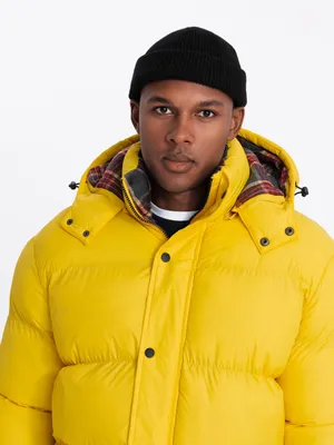 A man wearing a yellow puffer jacket and a black beanie.