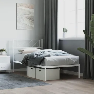 A white metal bed frame with a headboard, bedding, and storage boxes underneath, set in a bedroom with grey curtains and a painting on the wall.