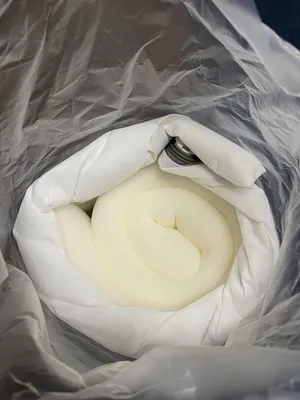 A rolled-up mattress topper inside its packaging.