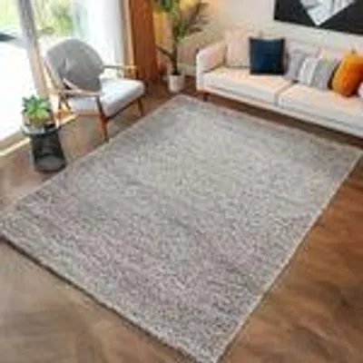 A living room scene with a rug, sofa, and chair.