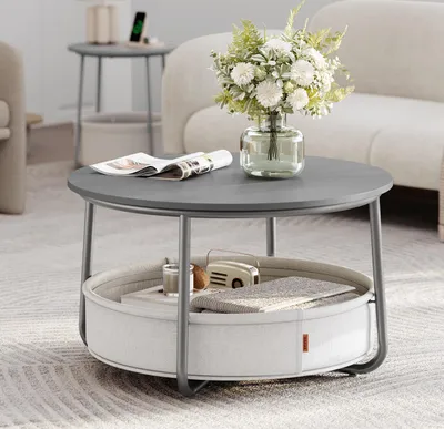 A round coffee table with storage is placed in a living room setting, next to a sofa and another side table.