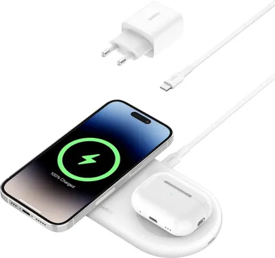 A white wireless charger with a phone and earbuds on it, along with a charging adapter and cable.