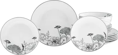 A set of white porcelain plates and bowls with a black floral design.