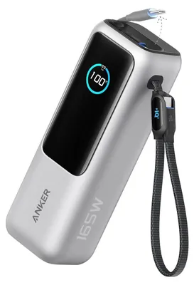 A silver Anker power bank with a digital display showing 100% charge, connected to a USB-C cable.