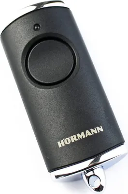 A black Hörmann remote control with a silver trim and a single button, shown against a white background.