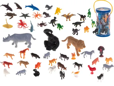 A collection of small plastic animal and dinosaur figures scattered on a white background, with a clear plastic bucket containing more figures in the upper right corner.
