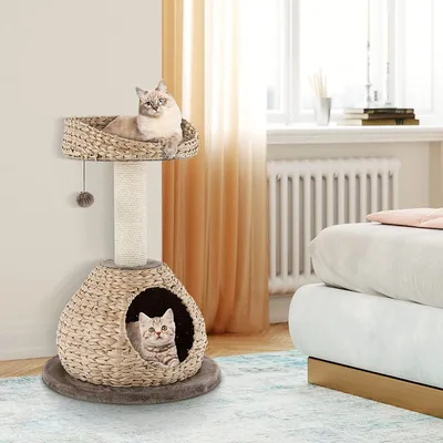 A cat tree with two cats in a room with a bed and window.