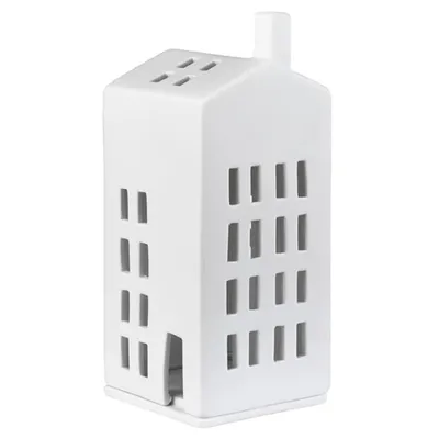A white ceramic house-shaped tea light holder with cut-out windows and a chimney.