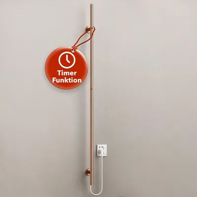 A copper-colored electric towel dryer mounted on a light gray wall, with a white electrical plug and cord connected to an outlet. A red circular tag with a clock icon and German text is hanging from the dryer.