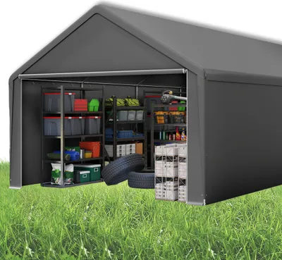 A grey storage tent filled with various items like storage bins, tires, and tools, set up on a grassy lawn.