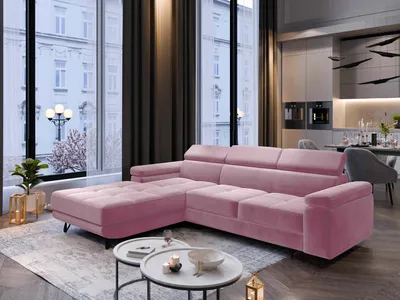 A pink sectional sofa is placed in a modern living room with large windows overlooking a city street.