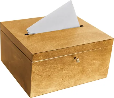 A wooden box with a slot on top and a keyhole on the front, with a piece of white paper sticking out of the slot.