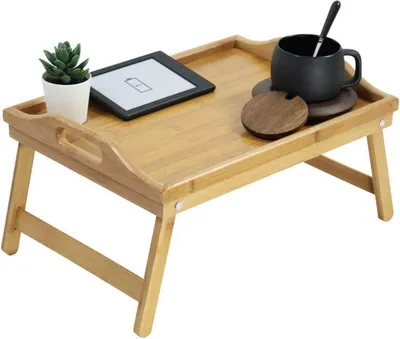 A bamboo bed tray with foldable legs, a plant, an e-reader, and a mug with a spoon on a white background.