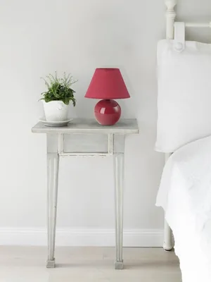 A bedside table with a lamp and a plant next to a bed.