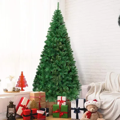 A decorated Christmas tree with gifts and a teddy bear in a room.