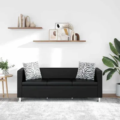 A black sofa with two zebra-print cushions is shown in a room with two shelves on the wall above it.