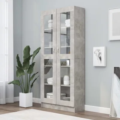 A tall, gray, glass-fronted cabinet filled with white dishes and towels, next to a large potted plant.