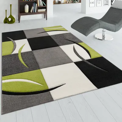 A modern living room with a rug, chaise lounge, and bookshelf.