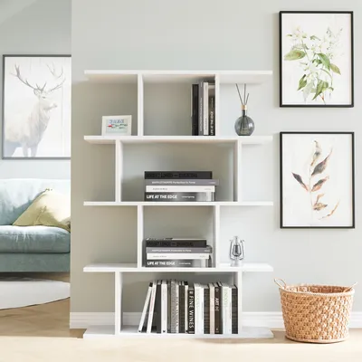 A modern white bookshelf filled with books and decorative items, next to a living room sofa.