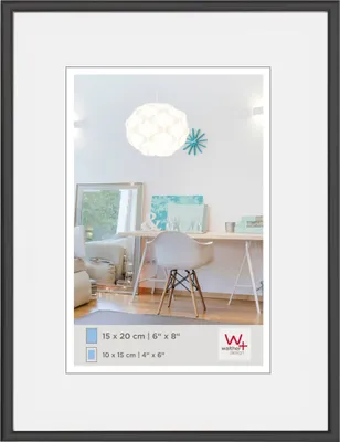 A framed picture of a desk area with a chair and a lamp.