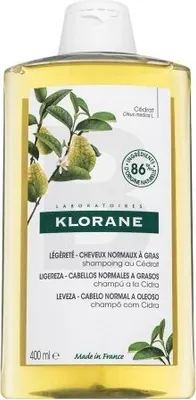 A bottle of Klorane shampoo with a label showing ingredients and product details.