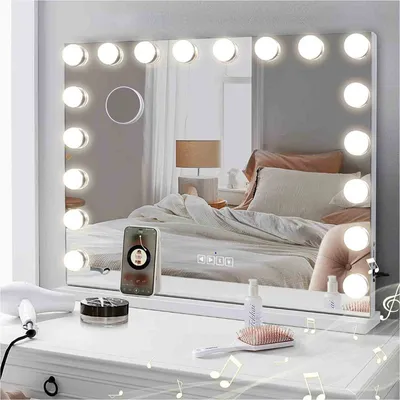 A vanity table with a Hollywood-style makeup mirror, a hairdryer, makeup products, and a phone playing music.