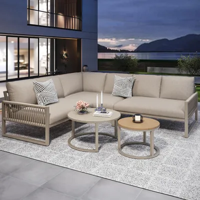 An outdoor lounge set on a patio at dusk with a lake and mountains in the background.