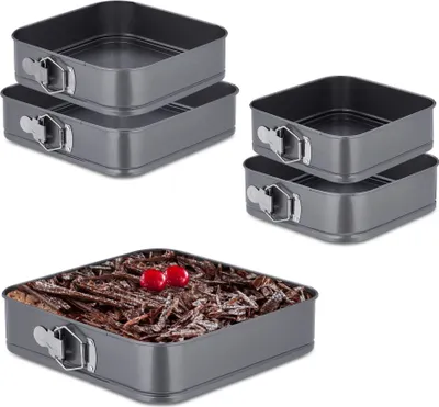 A set of square springform pans and one pan filled with cake.