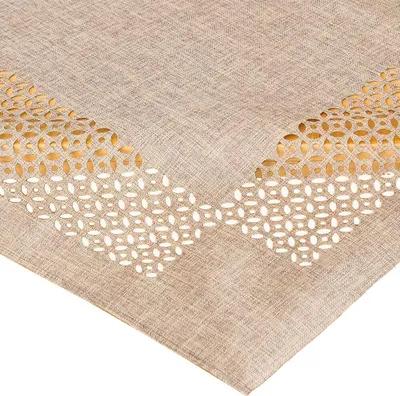 Close-up view of a beige tablecloth with a cut-out pattern.