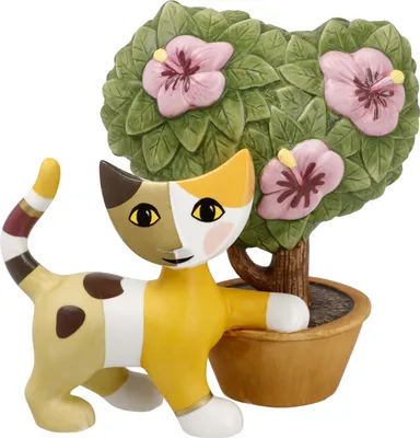 A ceramic cat figurine next to a potted plant with pink flowers.