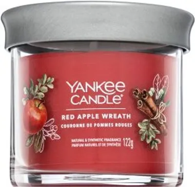 A Yankee Candle jar with a red label depicting apples and cinnamon sticks.