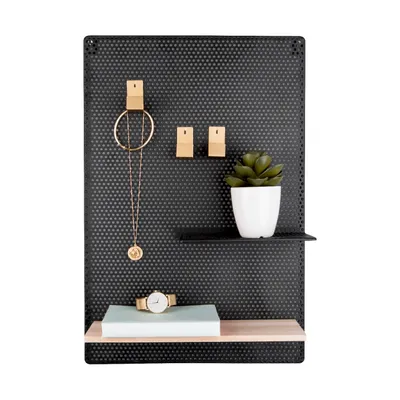 A black pegboard with accessories like a necklace, clips, a plant, a watch, and shelves.