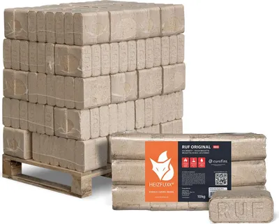 A stack of firewood briquettes on a pallet and a package of briquettes in the foreground.
