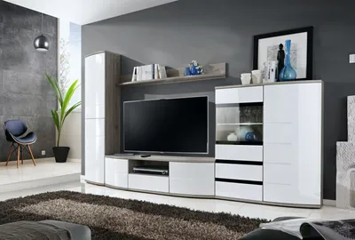 A modern living room with a large TV unit, a chair, and a plant.