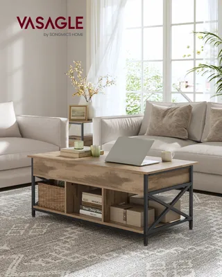 A living room scene featuring a coffee table with a laptop and decor, in front of a sofa and window.