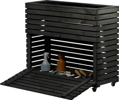 A dark gray wooden raised garden bed with storage underneath, showing gardening tools and a spray bottle.