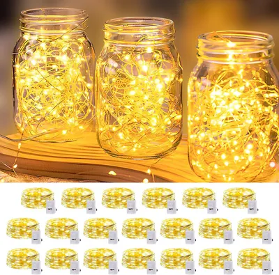 Three glass jars filled with warm white LED string lights, with a stack of individual LED string light spools below.