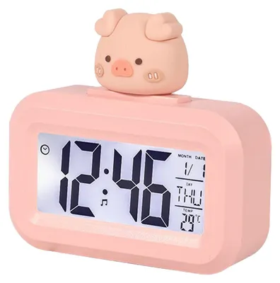 A pink digital alarm clock with a cute pig cartoon on top, displaying the time, date, and temperature.