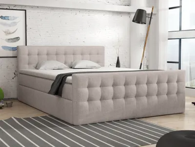 A bedroom scene featuring a large bed with a tufted headboard and frame, set against a white brick wall.