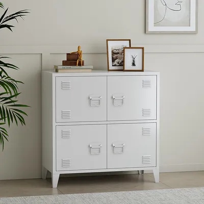 A white metal cabinet with four doors, styled like lockers, is shown in a room with a plant and framed pictures on top.