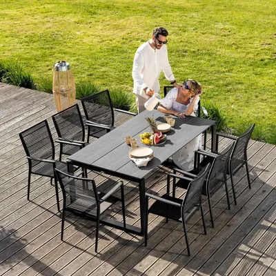 A couple is enjoying a meal at a table on a wooden deck, surrounded by grass.